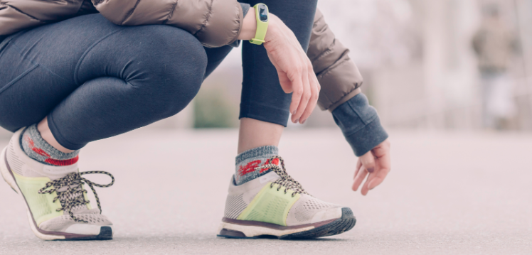 female kneeling with running shoes