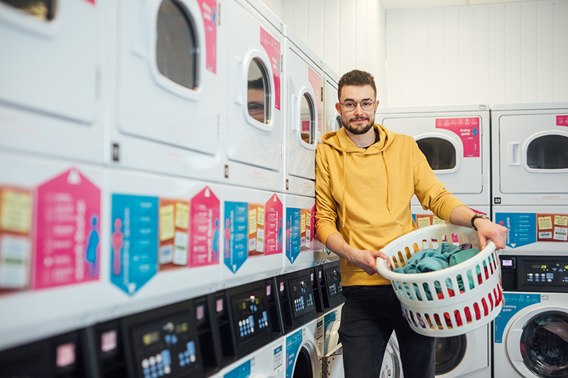 Student holding basket of laundry in Elms BT9 Laundry Room