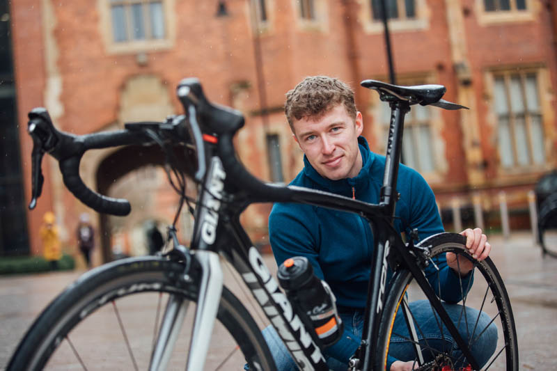 Craig fixing his bicycle on the main site of the Queen's Lanyon Building