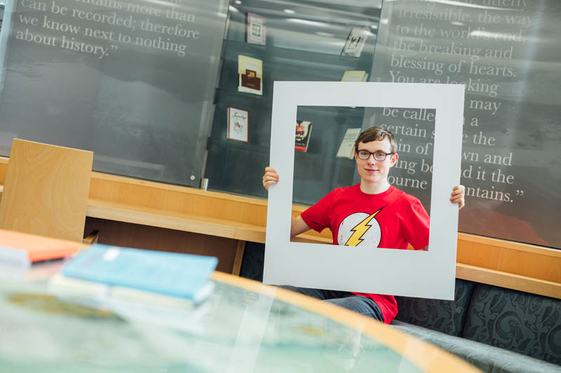 Image of student in CS Lewis room holding up large polaroid shot