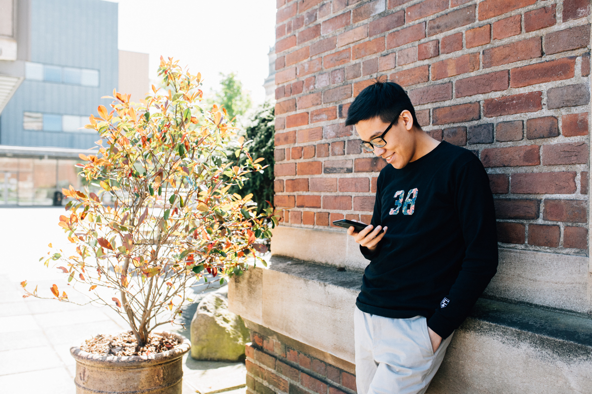 Image of student outside the SU Elmwood Building using mobile phone