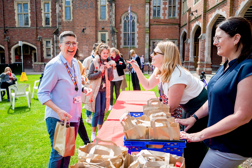 staff chatting and laughing at the Great Big Purple Picnic registration table in Queen's quad