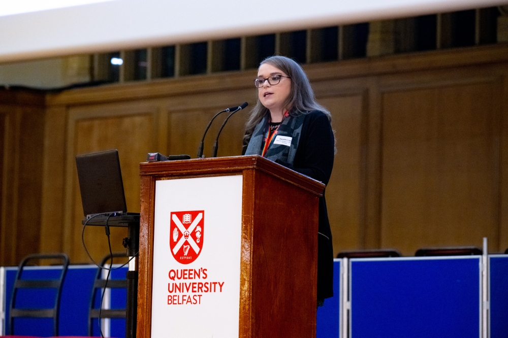 Dr Danielle Logan, postdoc and Co-Chair of Queen's Postdoc Society, presenting on stage at Queen's Postdoc Showcase 2023 in the Whitla Hall