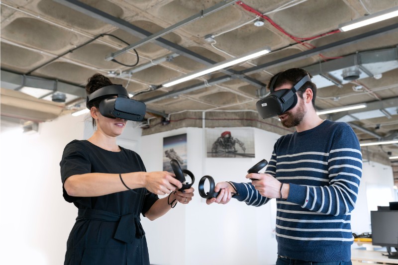 Two persons wearing VR headsets and gear