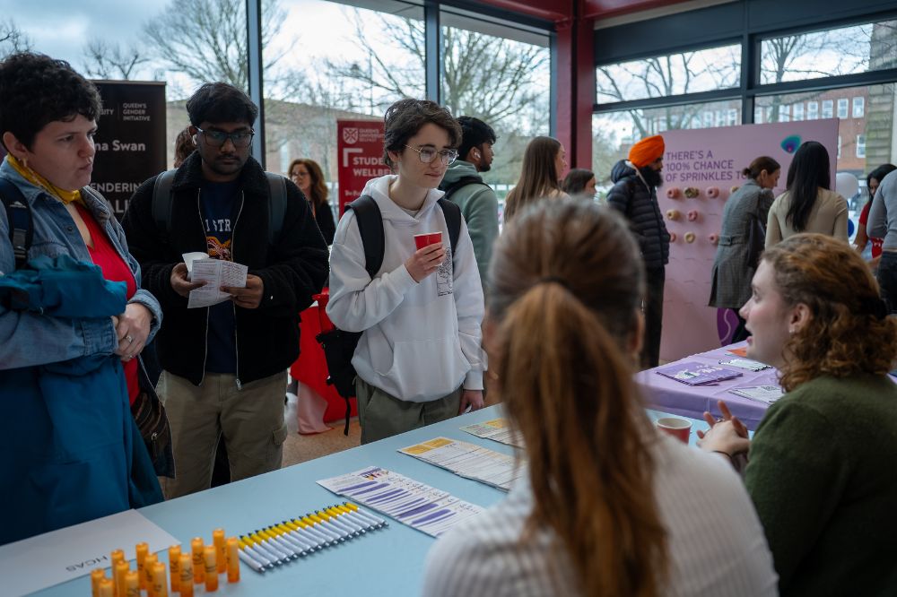 Students speaking with staff at an information table during a campus awareness event.