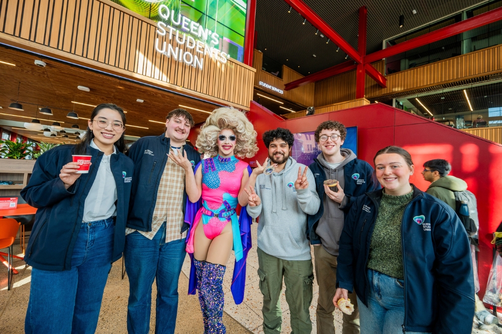 group of students posing with drag queen at the LGBTQueen's Celebration Showcase, One Elmwood