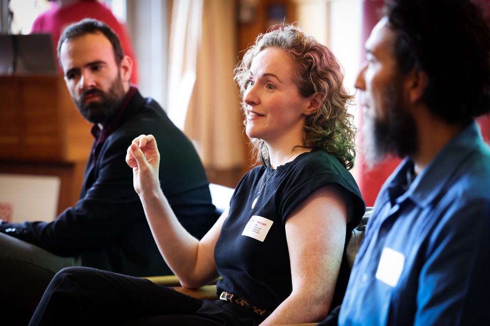 seated woman speaking as part of a three-person panel at an indoor event