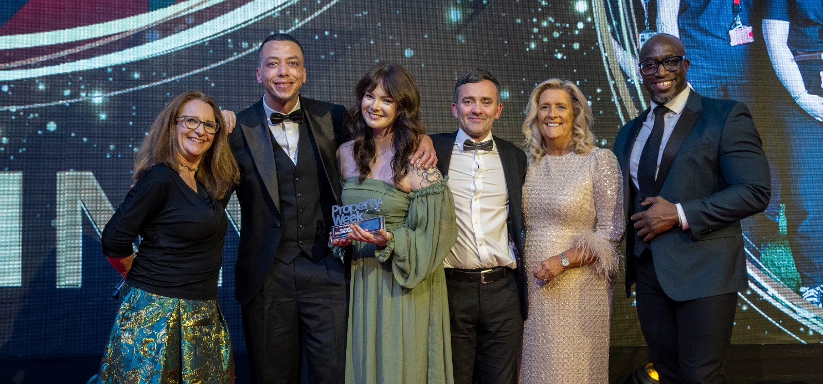 Three women and three men smiling and posing on stage at an awards ceremony. One of the women is holding a 'Property Week' trophy.